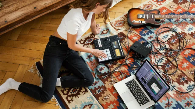 Musician on the floor making music with a Maschine controller and a laptop